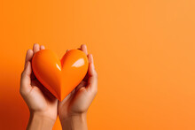 Hand Holds A Heart Love Shape On An Orange Background With Copy Space