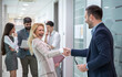 © Bojan - Cheerful business woman and happy businessman, old colleagues and office mates shaking hands after not seeing each other for a long time. Business handshake, old friendship and greeting deal concept.