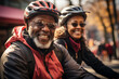 © Georgii - Elderly smiling couple in safety helmets ride bicycles together to stay fit and healthy. Happy African American seniors having fun on a bike ride on country road. Retired people lead active lifestyle.