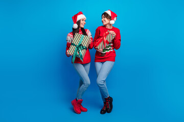 Poster - Full length photo of positive charming women santa elves wear ornament pullovers preparing x-mas gifts isolated blue color background