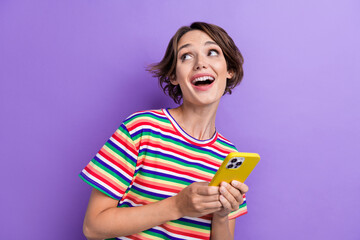 Poster - Portrait of pretty cheerful girl hold smart phone look empty space ad isolated on purple color background