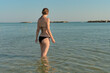 © AleksFil - A young woman enters the water against the backdrop of a seascape