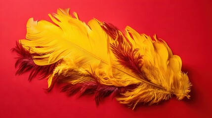 Wall Mural -  a yellow feather laying on a red surface with a red background.  generative ai