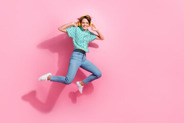 Poster - Full size portrait of excited nice girl jump hands touch headphones empty space isolated on pink color background