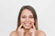 © Марина Демешко - Young caucasian blonde woman demonstrating her beautiful smile with fingers isolated on a white background. Teeth whitening. Oral hygiene, dental health care, perfect even teeth. Dentistry concept