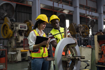 Warehouse of raw materials. Rolls of metal sheet, aluminum material. Male and female factory worker inspecting quality of rolls of galvanized or metal sheet in aluminum material warehouse