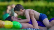 © Marco - Happy mother and child laying down in outdoor grass after swimming at pool. Little boy and mom affectionate bonding and embrace moment