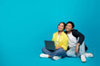 © Prostock-studio - Smiling millennial asian couple in casual use laptop, sit on floor, look at free space