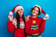© deagreez - Photo of positive girls in santa costume advertise traditional holly jolly gifts sale isolated blue color background