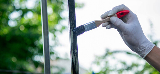 a man paints metal with black paint with a brush.