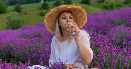 Wall Mural - A woman drinks wine in a lavender field. Selective focus.