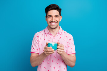 Poster - Photo of satisfied cheerful person beaming smile arms hold hot chocolate mug isolated on blue color background