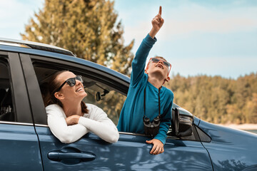 Wall Mural - Happy family road trip, mother and son looking out of car window enjoying nature wildlife