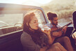 © Marko Geber - Friends sharing a musical moment during a sunlit road trip