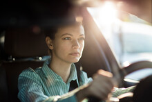 Focused woman driving in bright sunlight