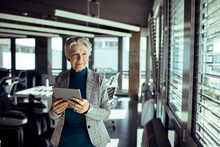 Senior Businesswoman Confidently Using A Tablet In A Modern Office