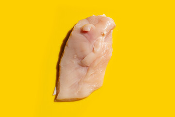 Wall Mural - Uncooked raw chicken breast fillets on yellow  background.