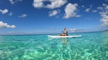 A woman on a stand up paddleboard paddling through the turquoise water on Cayman Islands