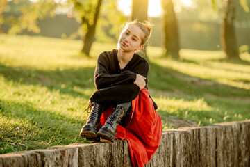 Canvas Print - Beautiful teenager girl in red skirt sitting in park outdoors at nature. Pretty teen model in trendy clothes at street