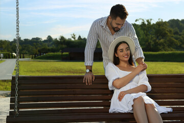 Wall Mural - Romantic date. Beautiful couple spending time together on swing bench outdoors