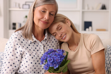 Sticker - Happy mature mother and her daughter with beautiful cornflowers at home