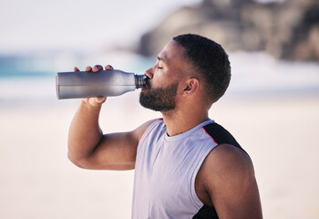 Wall Mural - Beach, exercise and man drinking water after running, workout or cardio fitness for health. Hydration, drink and thirsty male and runner person with bottle at sea for training, wellness or sports