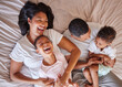 © Lumeez Ismail/peopleimages.com - Top view, love and black family in bedroom, playful and cheerful on weekend break, quality time or happiness. African American mother, father or children on bed, joyful or relax with support or laugh