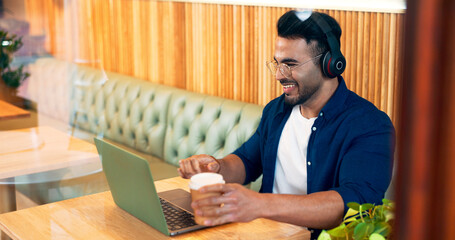 Canvas Print - Happy man in coffee shop with headphones, laptop and remote work, reading email and internet in restaurant. Computer, freelancer and copywriter in cafe, listening to music and drink in cup at table