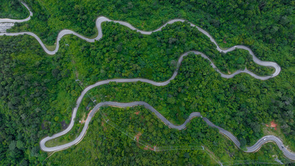 Wall Mural - Aerial View of road on mountain forest road, Countryside road passing through the green forrest and mountain.