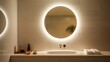 A sleek, round bathroom mirror with a built-in LED ring, illuminating its surroundings, set on a spotless white tableau.