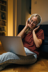 Wall Mural - Beautiful happy woman sitting on the floor at home and listening to music.