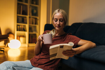 Wall Mural - Caucasian woman reading a book at home on the floor.