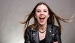 Portrait of a beautiful rocker woman in a black leather jacket on a studio background. Screaming girl isolted exemplifies youthful rebellion, alternative fashion, self-expression