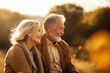 © Anoo - An elderly couple, a man and a woman, hugging in an autumn park. They look at each other with a loving gaze. Old people on a walk. Relationships in old age. Love and romance.