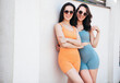 Two young beautiful smiling female in trendy summer cycling shorts, top clothes. Sexy carefree women posing in street at sunny day. Positive models having fun. Cheerful and happy. In sunglasses