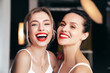 Closeup portrait of two young beautiful smiling brunette female with glamour evening makeup. Sexy women with healthy glowing face skin. Hot models with red lips posing over dark background