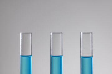 Poster - Close up of laboratory test tubes with blue liquid and copy space on white background