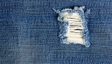 Blue Jeans With A White Stripe That Has Been Torn Off, Destroyed Torn Denim Blue Jeans Texture, Close-up Rip In Blue Denim Fabric, Revealing White Fabric Underneath
