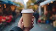 Close-up of hand holding disposable paper coffee cup, man's hand clinking glasses outdoors on blurred background