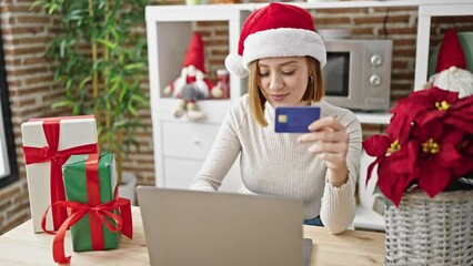 Wall Mural - Young blonde woman shopping with laptop and credit card celebrating christmas at dinning room