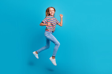 Wall Mural - Full length photo of satisfied cute small schoolgirl dressed striped t-shirt run at sale empty space isolated on blue color background