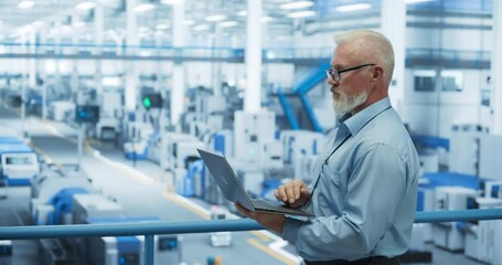 Leinwandbilder - Portrait of a Handsome Middle Aged Engineer with Glasses Using Laptop Computer and Looking Around a Factory Facility with Equipment Producing Modern Electronic Components for Different Industries