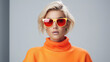 © Santy Hong - Fashionable confident blonde woman wearing trendy orange sweatshirt, color sunglasses, posing on white background.