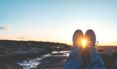 Woman reaching the destination and sitting on top of hill or mountain at sunrise.   Local tourism concept.