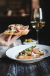 © pridneprovskiy - Appetizing bruschetta with thin pieces of meat on a dark background. Food photography.