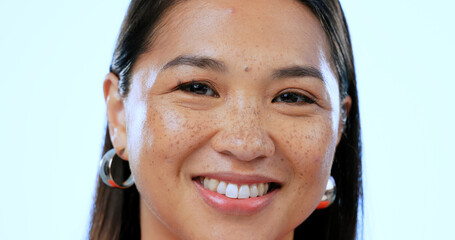 Wall Mural - Happy, smile and portrait of Asian woman in a studio with positive, good and confident attitude. Excited, headshot and closeup face of young female person with happiness isolated by blue background.