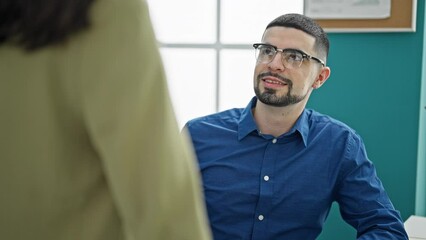 Poster - At the office, two elegant workers, a man and a woman, speak and smile together, exuding a professional lifestyle while working. sitting at their desk, they express business success as a team.