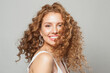 © artmim - Cheerful happy woman with long natural healthy brown curly hair and cute smile looking at camera on white background. Hair care, hair treatment, wellness, joy and cosmetology concept