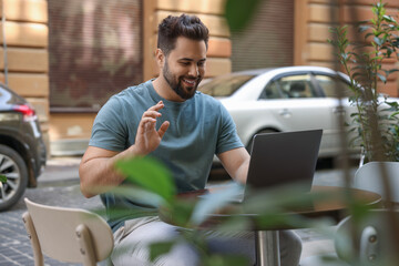 Canvas Print - Handsome young man working on laptop at table in outdoor cafe