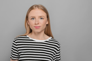 Wall Mural - Portrait of beautiful young woman in striped t-shirt on grey background. Space for text